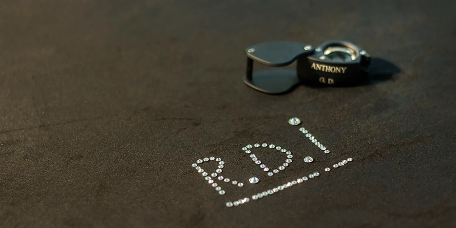 The letters R.D.I. spelled out in loose diamonds, with a jeweller’s loupe